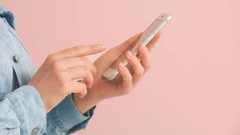 Imagem dos braços de uma mulher mexendo no celular