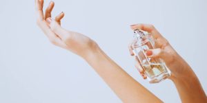 Mulher espirrando perfume no próprio pulso