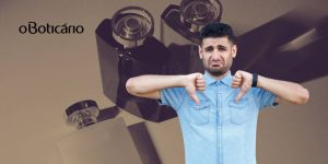 Montagem com homem chateado fazendo sinal de desaprovação, frascos de perfumes ao fundo e a logomarca do Boticário ao lado