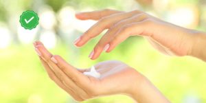 Mãos femininas espalhando creme hidratante