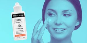 Close no rosto de uma mulher passando protetor solar na bochecha; ao lado, um frasco do Protetor Solar PS-02 FPS50 da Principia